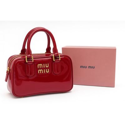 حقيبة Miu Miu باللون الأحمر اللامع مزوّدة بشعار ذهبي.