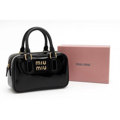 حقيبة Miu Miu باللون الأسود اللامع مزوّدة بشعار ذهبي.